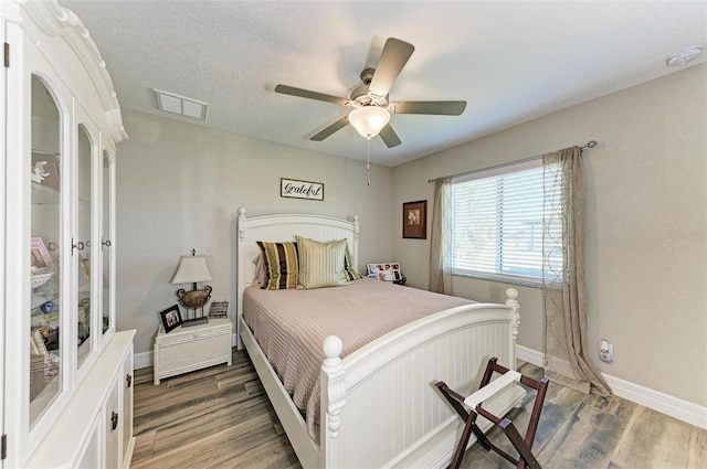 bedroom featuring a textured ceiling, ceiling fan, and dark wood-type flooring