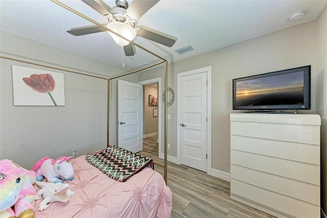 bedroom with ceiling fan, light hardwood / wood-style floors, and a textured ceiling