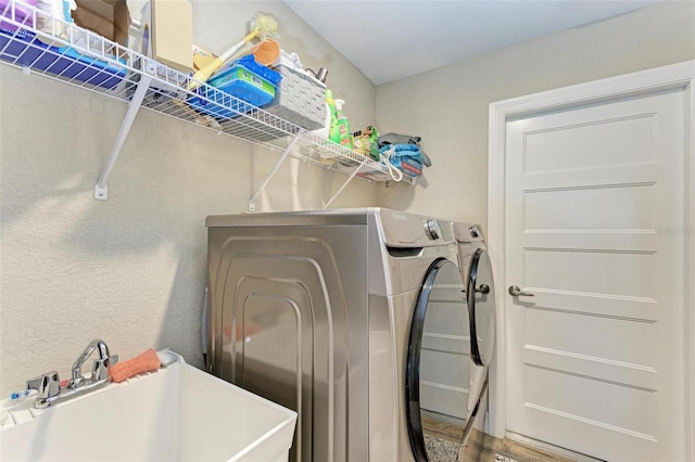 laundry area featuring washing machine and dryer, sink, and hardwood / wood-style flooring