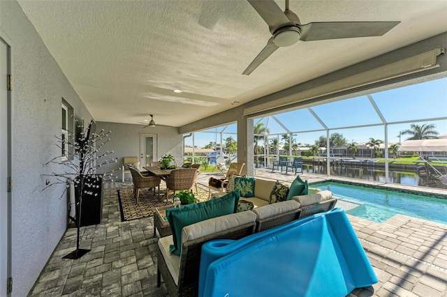 view of pool featuring outdoor lounge area, ceiling fan, a water view, glass enclosure, and a patio