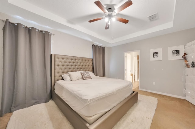 carpeted bedroom featuring ceiling fan and a raised ceiling