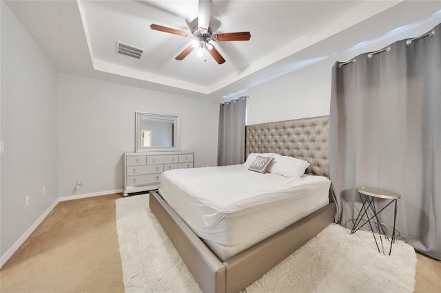 carpeted bedroom featuring ceiling fan and a tray ceiling