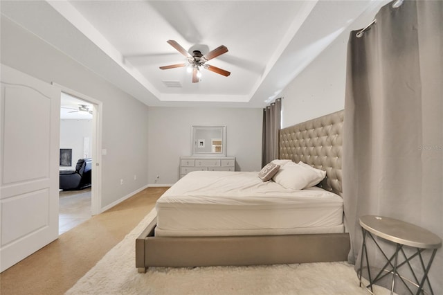 carpeted bedroom with ceiling fan and a tray ceiling