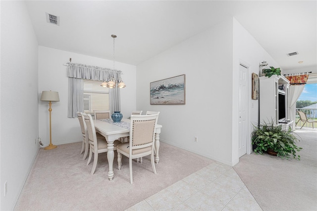 carpeted dining area with a chandelier