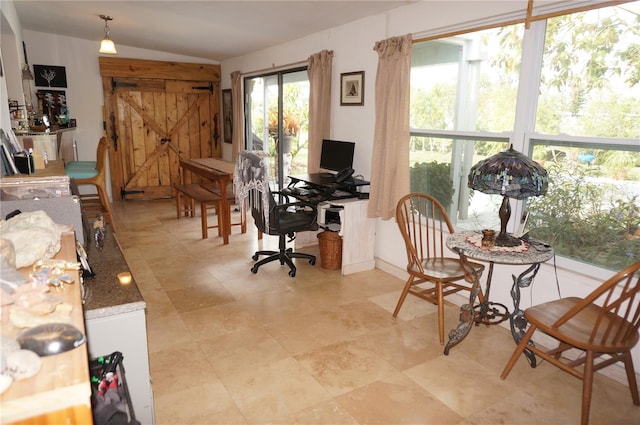 office with a barn door and vaulted ceiling