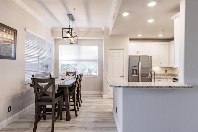 dining room featuring sink, light hardwood / wood-style flooring, and ornamental molding