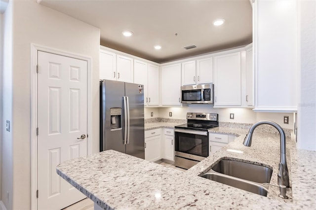 kitchen with light stone counters, sink, white cabinets, and stainless steel appliances