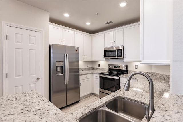 kitchen featuring white cabinets, stainless steel appliances, and light stone counters