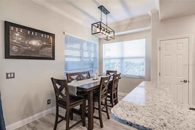 dining room featuring light hardwood / wood-style floors, ornamental molding, and an inviting chandelier