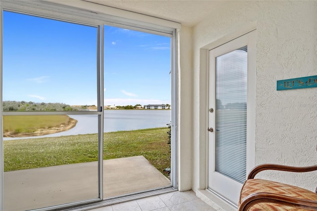 doorway to outside with light tile patterned floors, a textured ceiling, and a water view