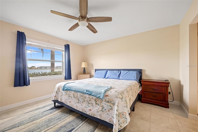 tiled bedroom with ceiling fan and a water view