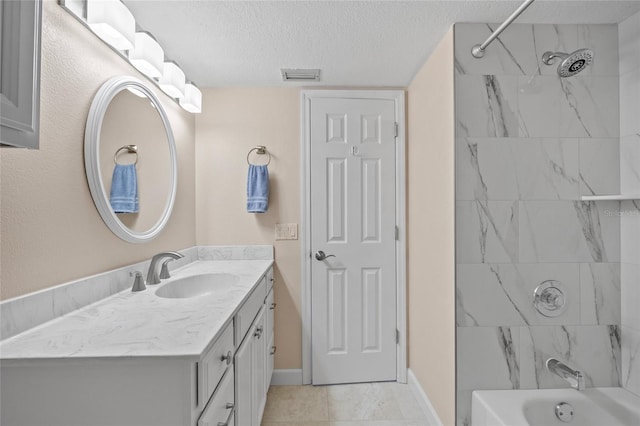 bathroom with vanity, a textured ceiling, and tiled shower / bath combo