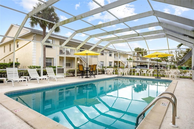 view of pool featuring glass enclosure and a patio