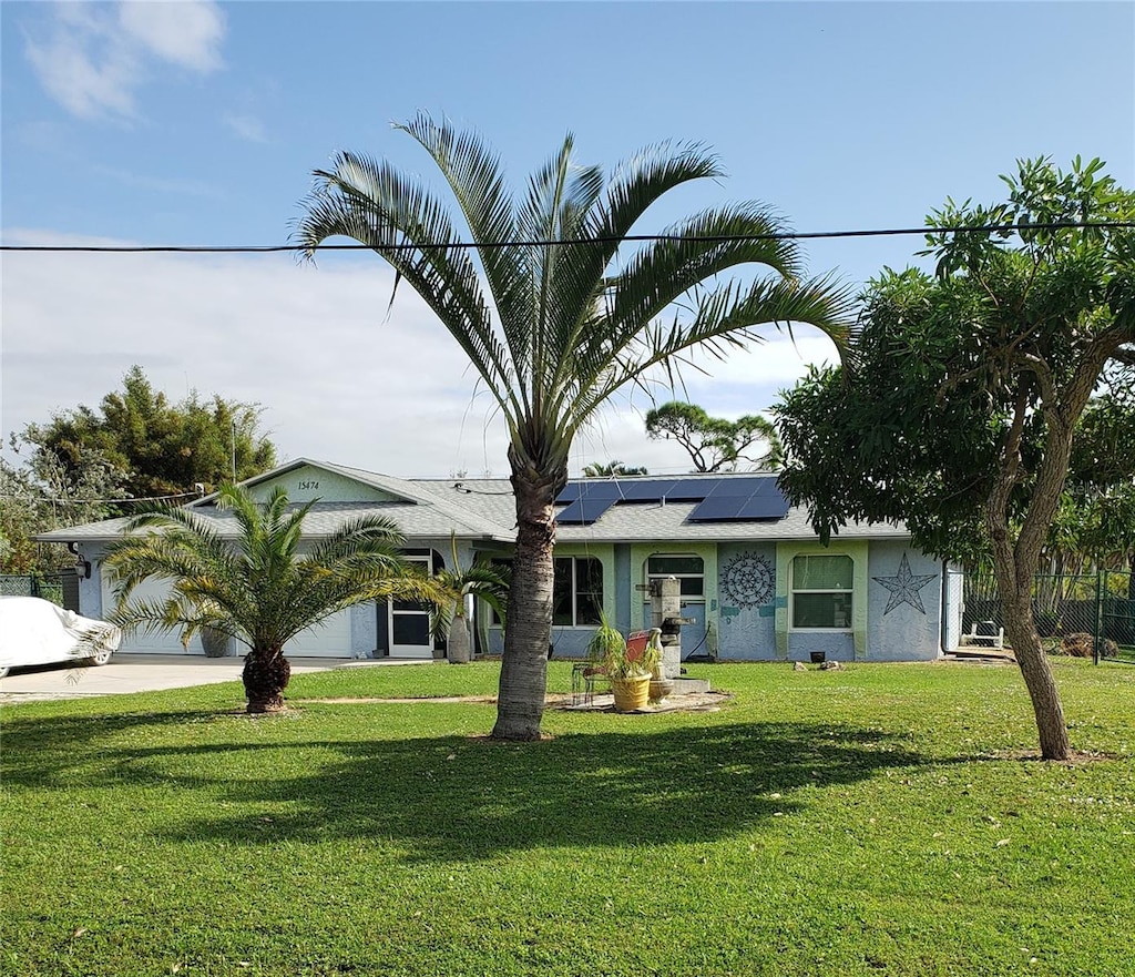 ranch-style house with a garage, a front yard, and solar panels