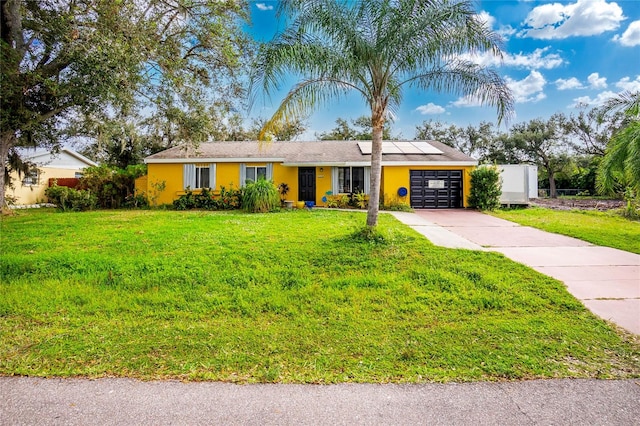 ranch-style home featuring a garage, a front yard, and solar panels