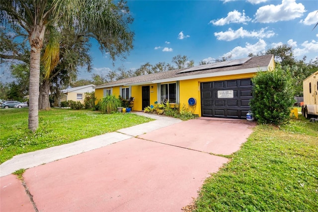 ranch-style home featuring a garage, a front yard, and solar panels