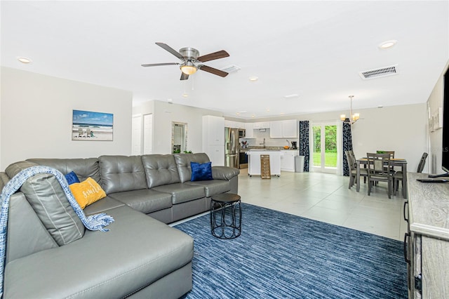 living room with tile patterned flooring and ceiling fan with notable chandelier