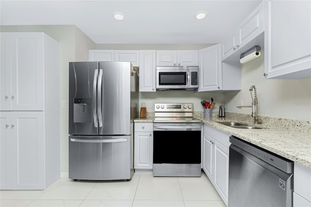 kitchen with white cabinets, stainless steel appliances, light stone counters, and sink