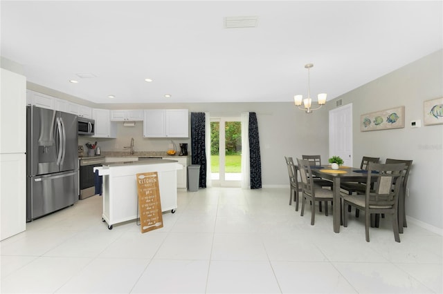 kitchen with a notable chandelier, appliances with stainless steel finishes, light countertops, a center island, and white cabinetry