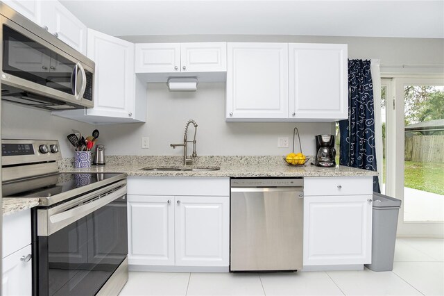 kitchen with a sink, appliances with stainless steel finishes, light stone countertops, and white cabinetry