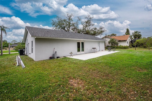 rear view of house featuring a yard, central AC, a patio area, and stucco siding