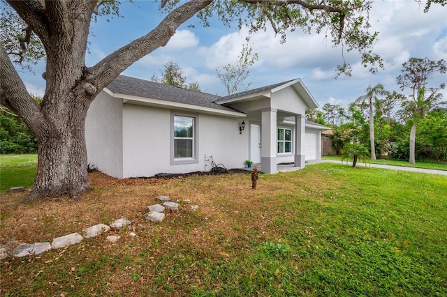 view of side of home featuring a garage, stucco siding, a yard, and a shingled roof