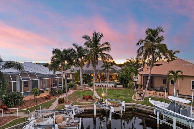 exterior space with a water view, a lanai, and a lawn