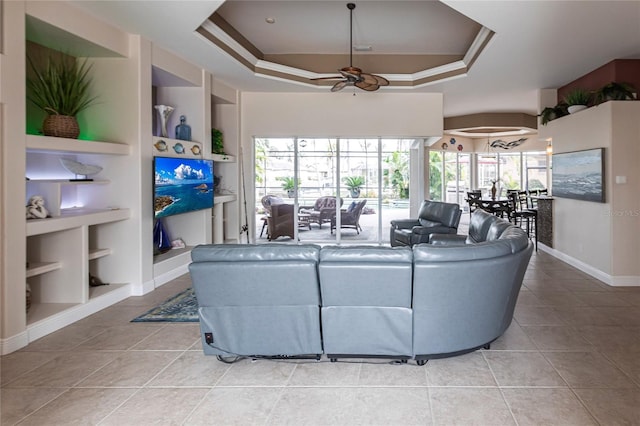 tiled living room featuring built in features, ceiling fan, and a tray ceiling