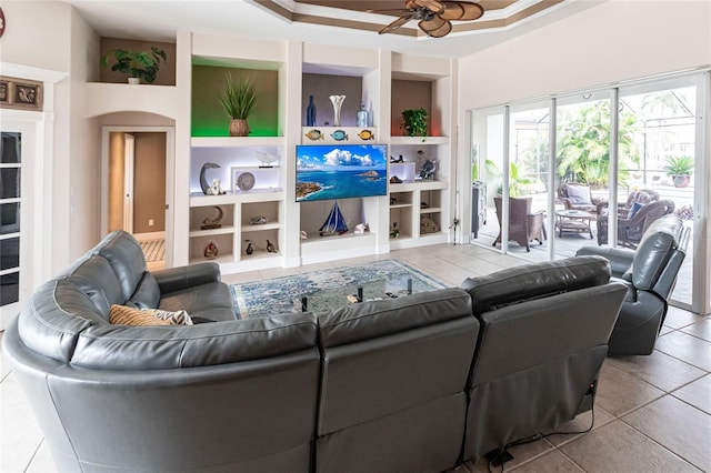 tiled living room featuring built in shelves, ceiling fan, and a tray ceiling