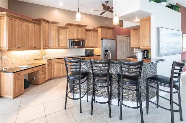 kitchen with light tile patterned floors, decorative backsplash, a breakfast bar area, and stainless steel appliances