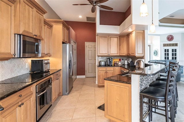 kitchen featuring sink, light tile patterned floors, kitchen peninsula, pendant lighting, and stainless steel appliances