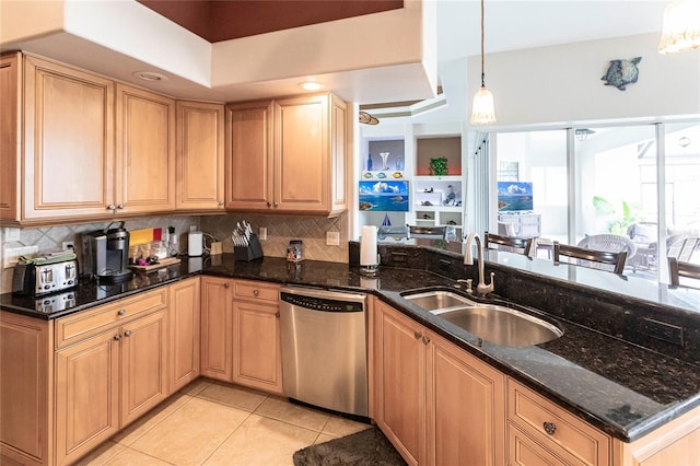 kitchen featuring pendant lighting, stainless steel dishwasher, sink, and dark stone countertops