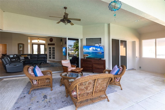 living room with ceiling fan, vaulted ceiling, french doors, and a textured ceiling