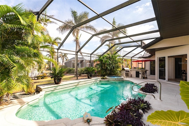 view of swimming pool with a patio, an outdoor kitchen, area for grilling, an in ground hot tub, and glass enclosure