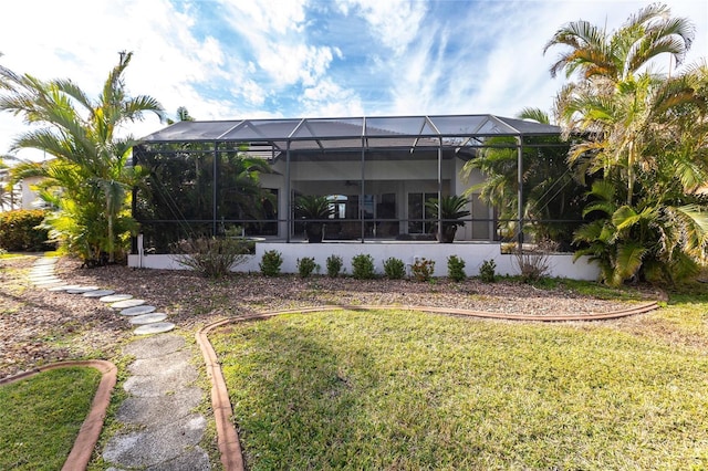 back of property with a lanai and a lawn