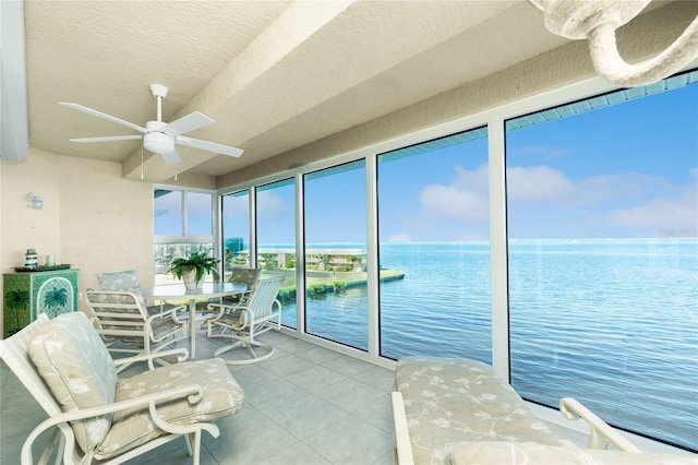 sunroom featuring ceiling fan and a water view