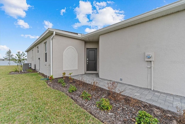 property entrance with a lawn and central AC unit