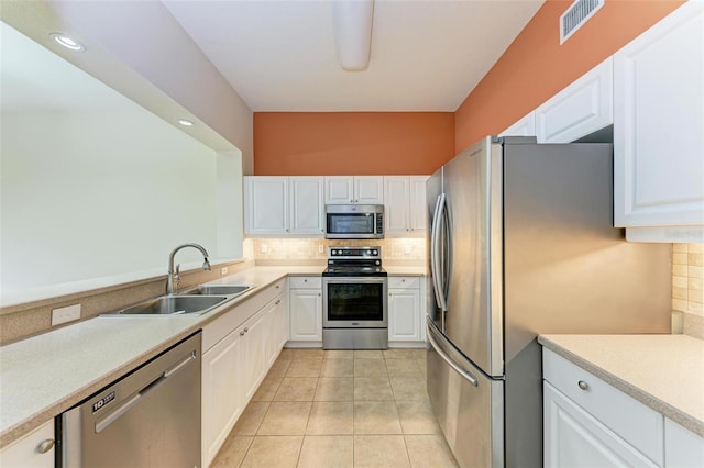 kitchen featuring appliances with stainless steel finishes, tasteful backsplash, sink, light tile patterned floors, and white cabinets