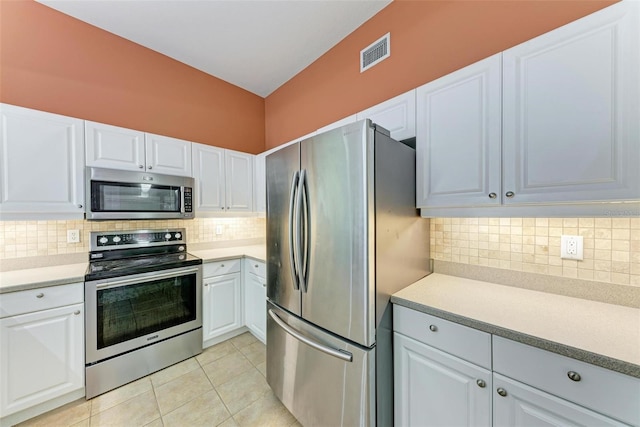 kitchen featuring white cabinets, light tile patterned floors, stainless steel appliances, and tasteful backsplash