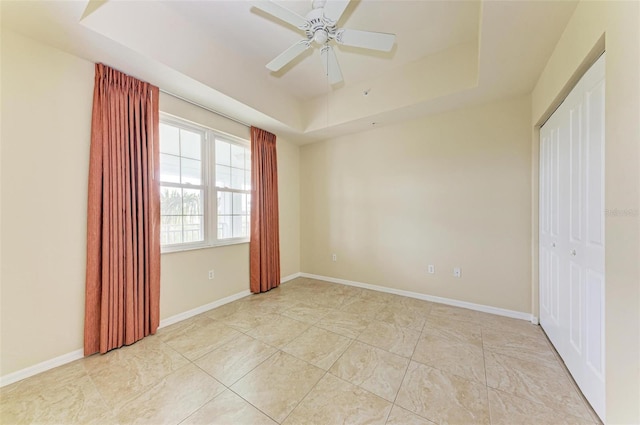 unfurnished bedroom with ceiling fan, a raised ceiling, and a closet