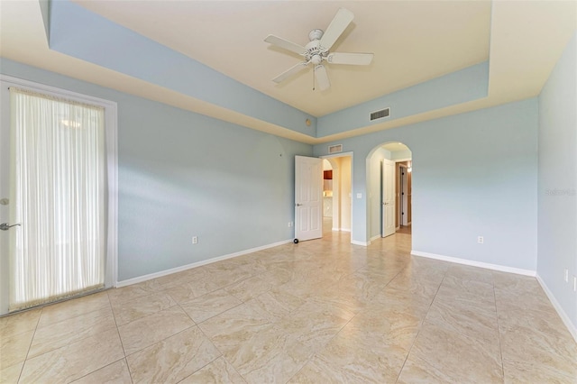 empty room featuring a raised ceiling and ceiling fan