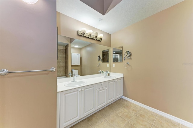 bathroom with a textured ceiling, tile patterned flooring, vanity, and vaulted ceiling