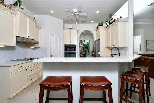 kitchen with a kitchen breakfast bar, cream cabinets, and stainless steel appliances