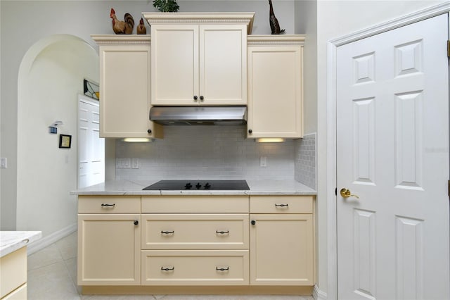 kitchen with black electric stovetop, backsplash, light tile patterned floors, and cream cabinets