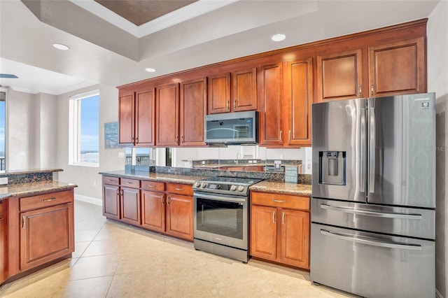 kitchen featuring dark stone counters, stainless steel appliances, and ornamental molding