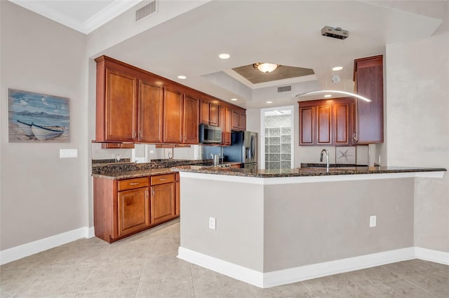 kitchen with kitchen peninsula, crown molding, dark stone countertops, and stainless steel appliances