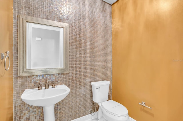 bathroom with sink, tile walls, and toilet