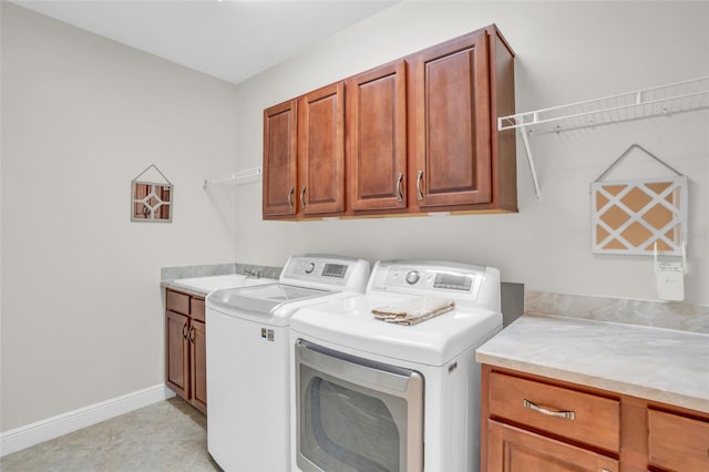 laundry room with washer and clothes dryer, cabinets, and light tile patterned floors