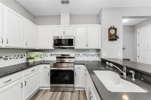 kitchen featuring sink, white cabinets, decorative backsplash, hardwood / wood-style flooring, and stainless steel appliances