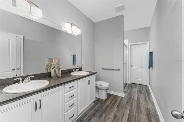 bathroom with vanity, hardwood / wood-style floors, a shower with door, and toilet